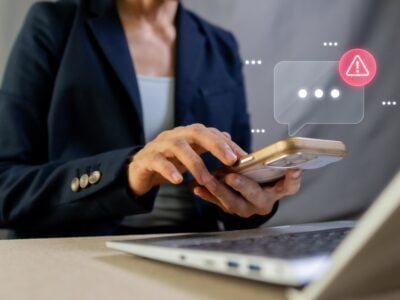 Business woman using her mobile phone which appears to be flagging some security risks